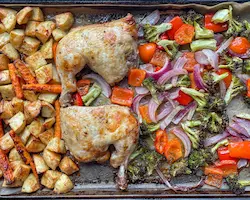 Chicken legs with potatoes, carrots and broccoli roasted on a sheet pan.