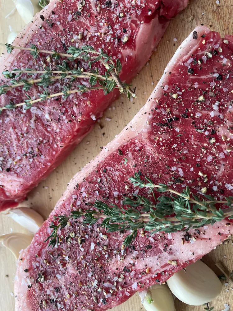 uncooked sirloin Sirloin steak, seasoned with salt and pepper, garlic and thyme.