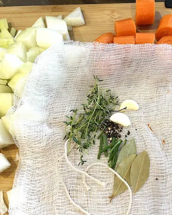 spice bag ingredients - bay leaf, parsley, peppercorns, garlic on cheesecloth with a string. spice bag ingredients - bay leaf, parsley, peppercorns, garlic on cheesecloth with a string.