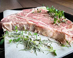 raw steak on a plate with rosemary