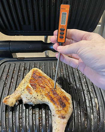 testing a chicken leg for doneness with a meat thermometer testing a chicken leg for doneness with a meat thermometer