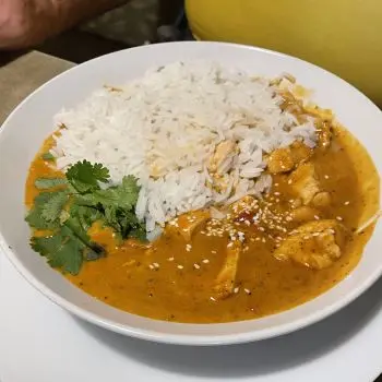 Red Thai curry in bowl with white rice and parsley