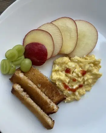 toddler breakfast of scrambled eggs, apple and toast
