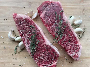 Uncooked sirloin steak seasoned with salt and pepper