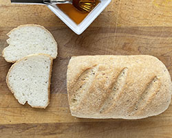 gluten free white bread with two slices on wooden cutting board.