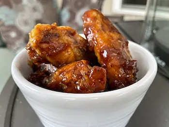 honey garlic glazed chicken wings in a white bowl.
