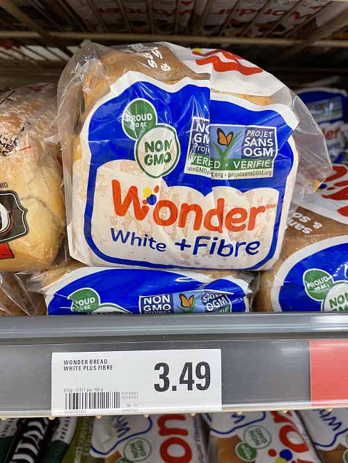 Wonderbread wheat bread on supermarket shelf with price.