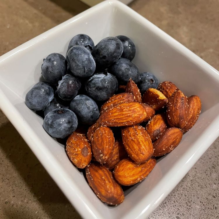 Almonds and blueberries in a square white bowl