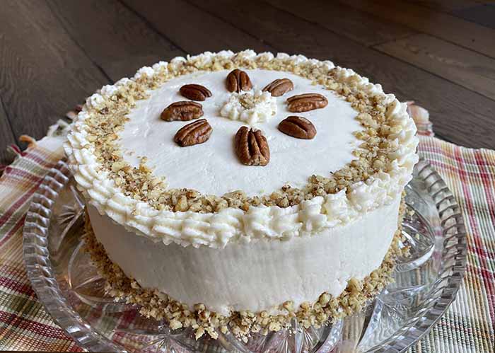 Whole carrot cake decorated with buttercream frosting and pecans