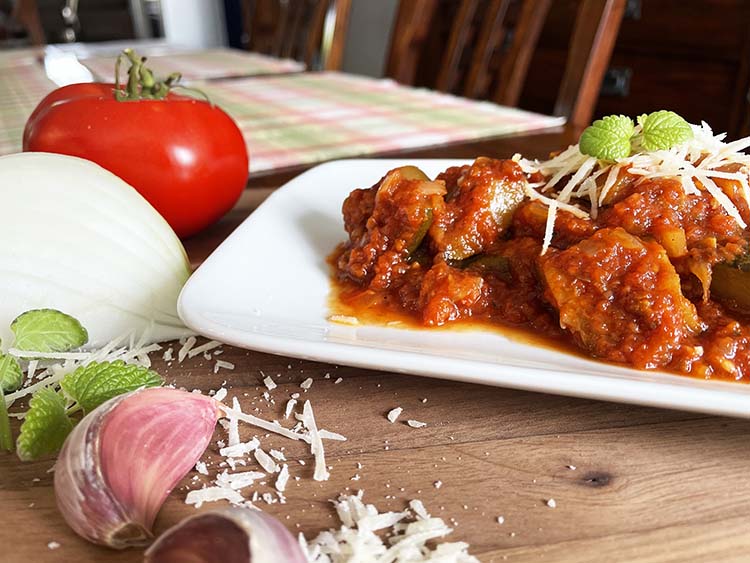 Plated zucchini stew with tomato, onion, garlic and mint on side. Plated zucchini stew with tomato, onion, garlic and mint on side.